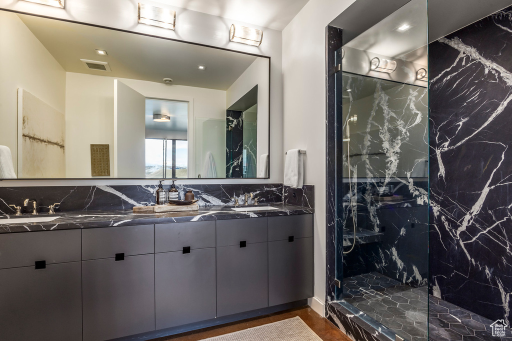 Full bathroom with double vanity, a marble finish shower, and decorative backsplash
