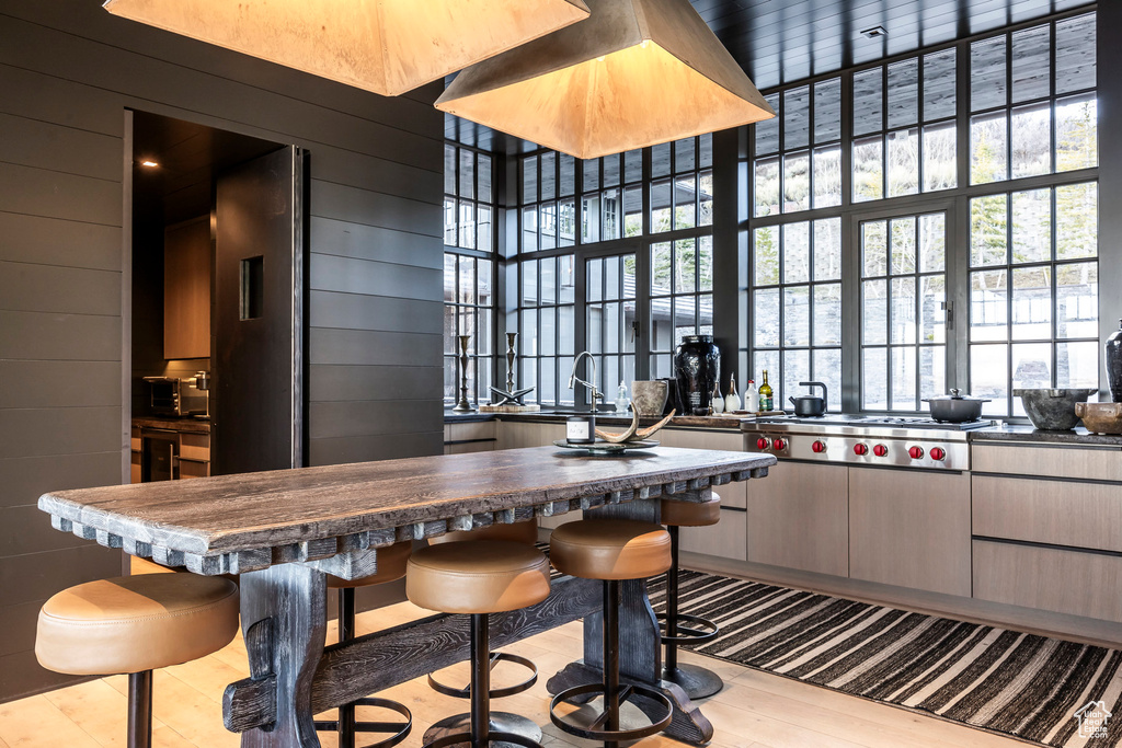 Kitchen featuring a breakfast bar area, wood finished floors, stainless steel gas stovetop, and dark countertops