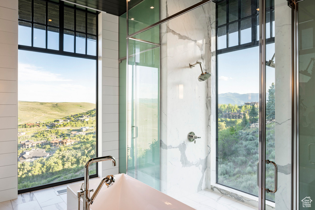 Full bath with a freestanding tub, a stall shower, a mountain view, and marble finish flooring