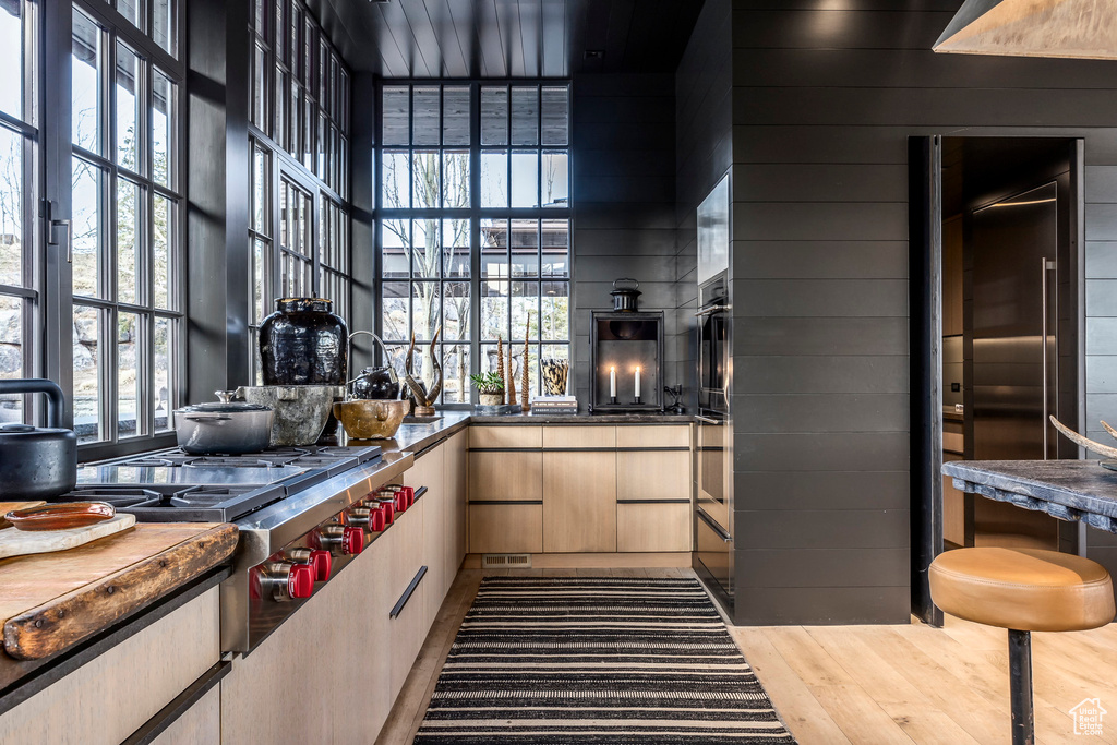 Kitchen featuring stainless steel gas cooktop, modern cabinets, wood finished floors, dark countertops, and light brown cabinetry