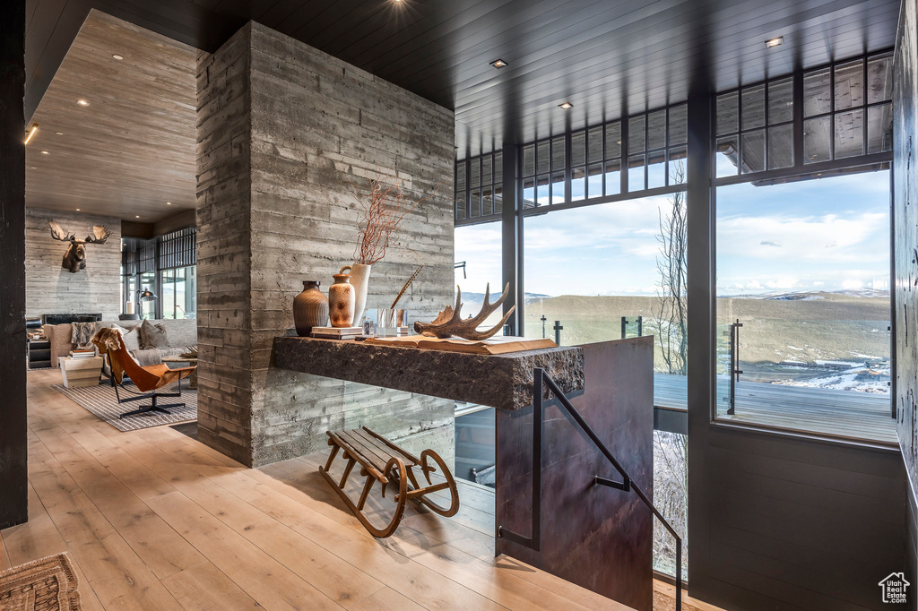 Kitchen featuring wood-type flooring, a stone fireplace, recessed lighting, and a towering ceiling