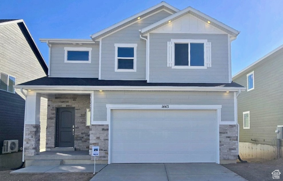 Craftsman-style home featuring stone siding, ac unit, a garage, concrete driveway, and board and batten siding