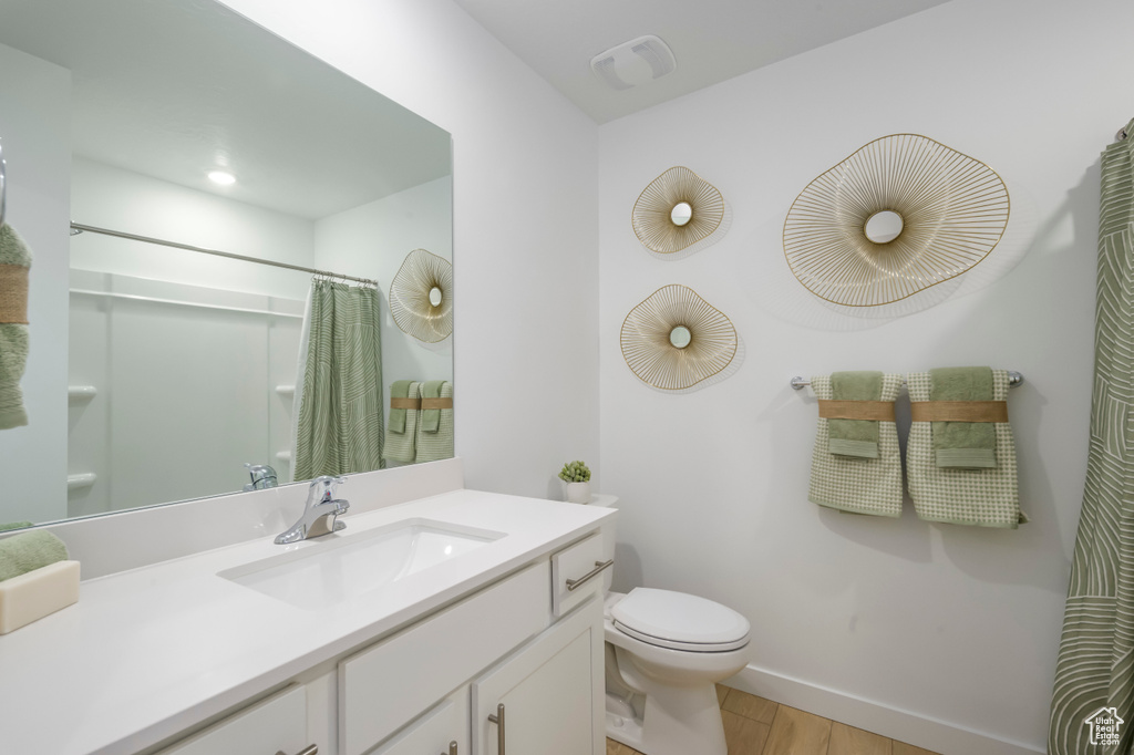 Bathroom featuring toilet, curtained shower, vanity, wood finished floors, and baseboards