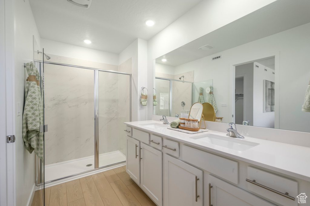 Full bath with a marble finish shower, visible vents, a sink, and wood finished floors