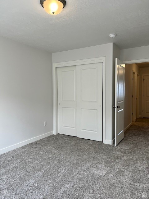 Unfurnished bedroom with carpet floors, a closet, and baseboards