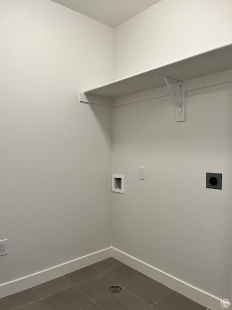 Clothes washing area featuring electric dryer hookup, laundry area, washer hookup, dark tile patterned flooring, and baseboards