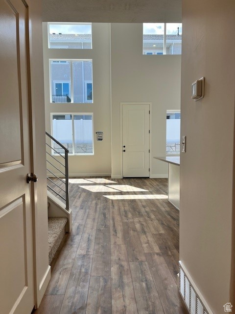 Entryway featuring visible vents, baseboards, a towering ceiling, hardwood / wood-style flooring, and stairs