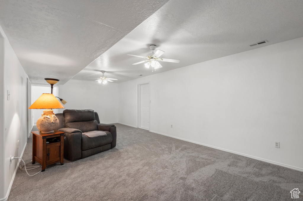Sitting room featuring ceiling fan, carpet flooring, a textured ceiling, and baseboards