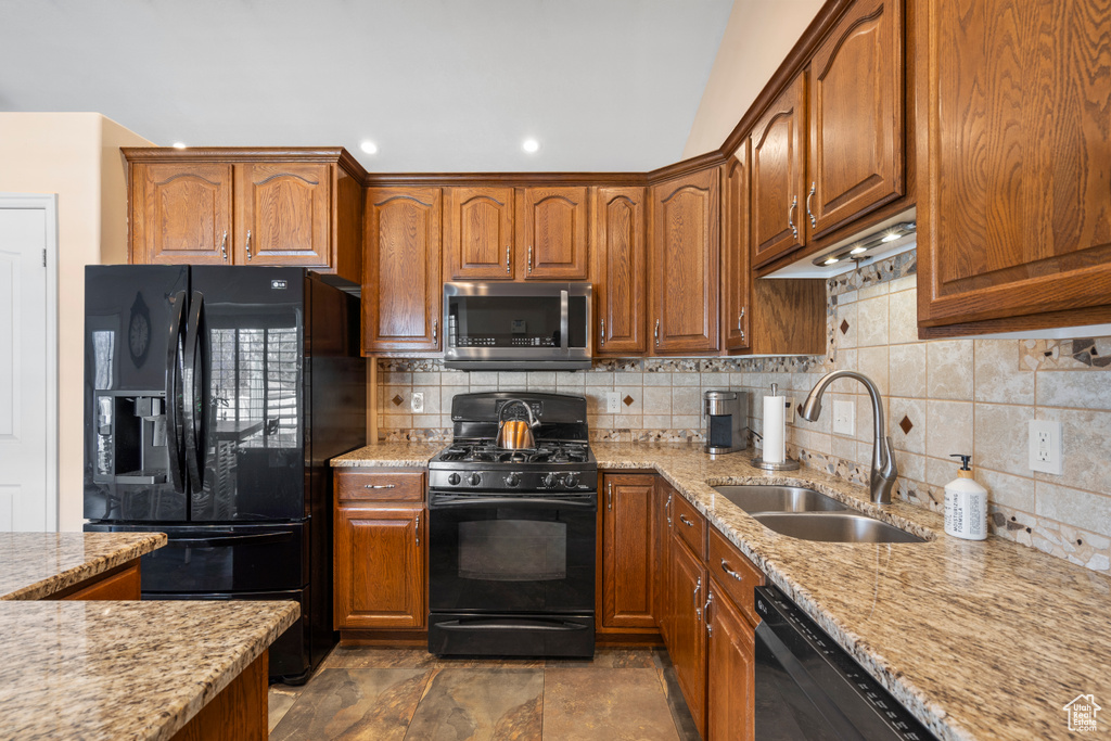 Kitchen with black appliances, a sink, decorative backsplash, light stone countertops, and recessed lighting