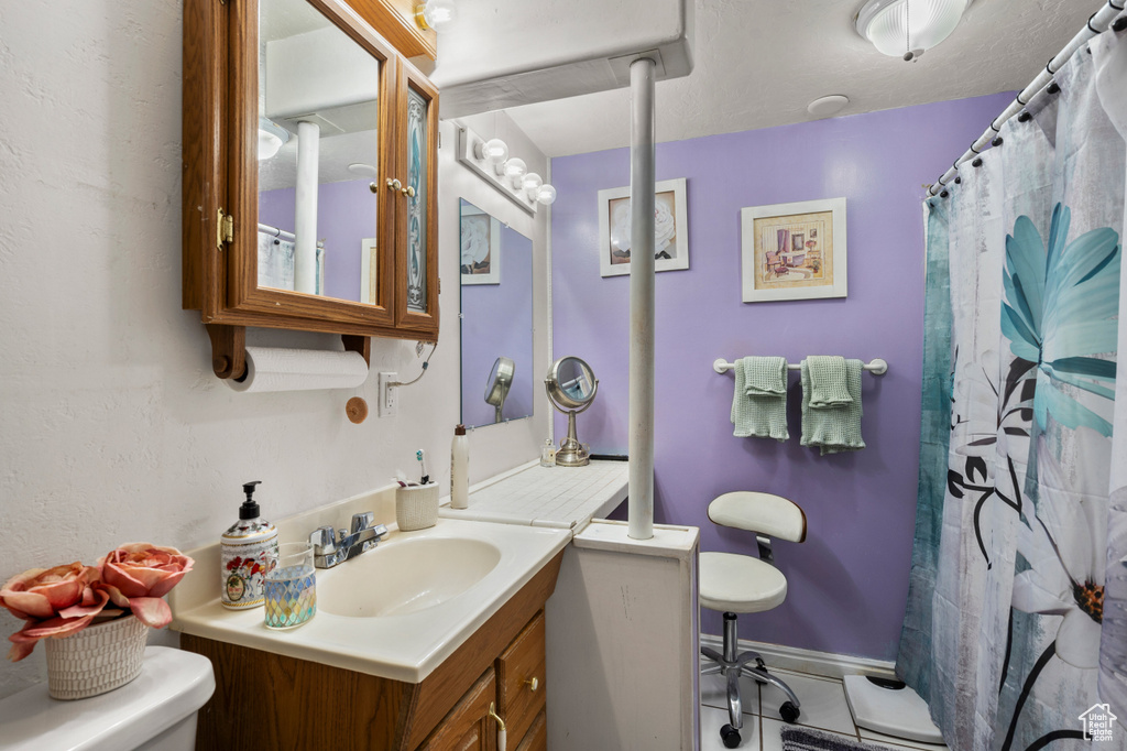 Full bathroom featuring toilet, vanity, tile patterned floors, and curtained shower