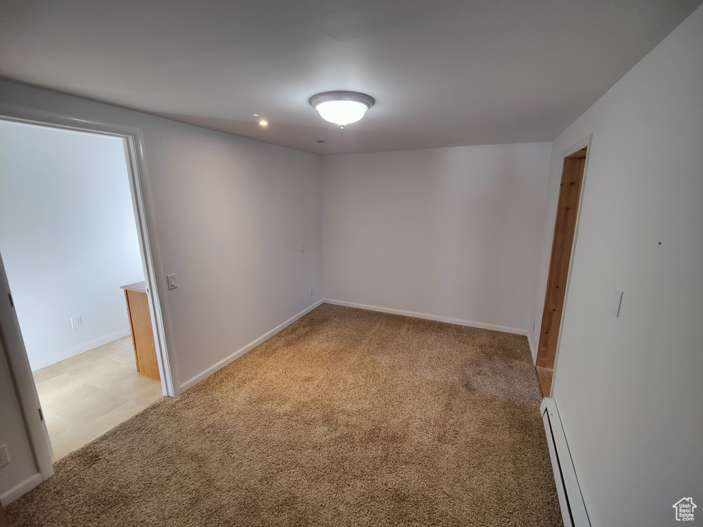 Spare room featuring recessed lighting, baseboards, light colored carpet, and a baseboard radiator