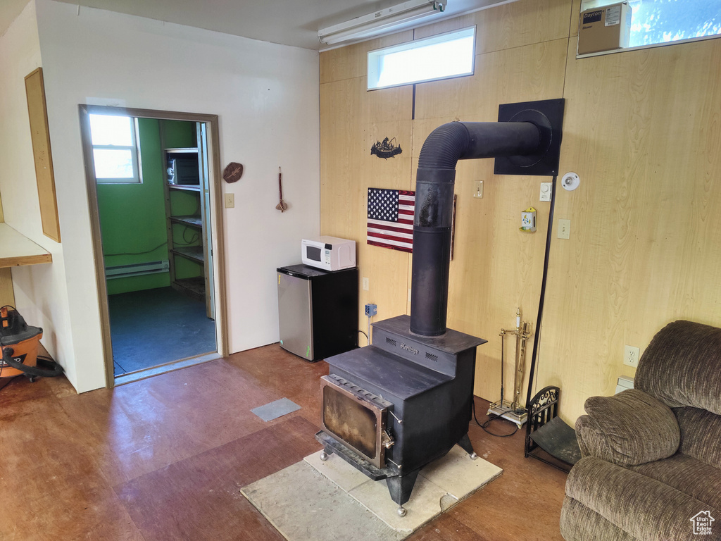 Living room featuring a baseboard heating unit and a wood stove