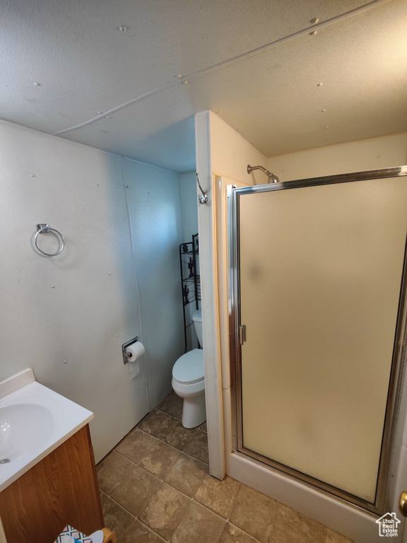 Bathroom with vanity, a shower stall, and toilet