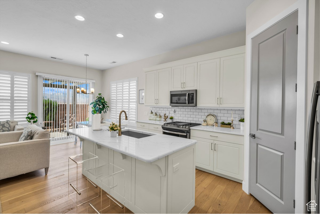 Kitchen featuring recessed lighting, tasteful backsplash, appliances with stainless steel finishes, a sink, and light wood-style floors