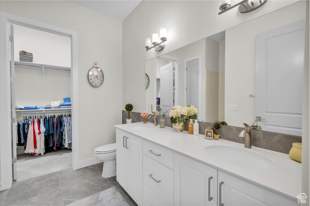 Full bathroom featuring double vanity, a walk in closet, and a sink