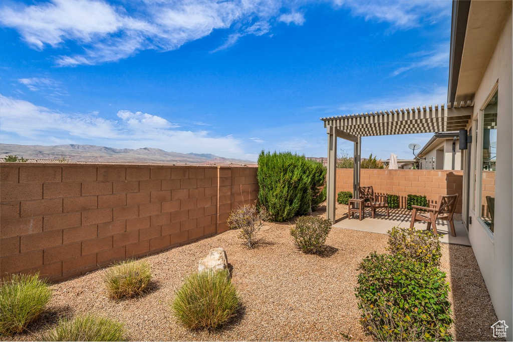 View of yard featuring a fenced backyard, a pergola, a mountain view, and a patio area
