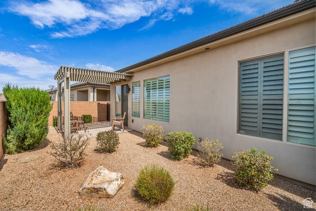 View of side of property with a patio, stucco siding, fence, and a pergola