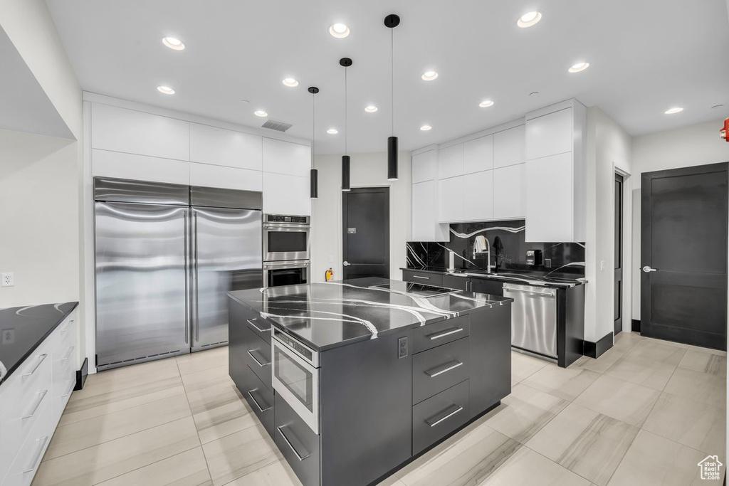 Kitchen with modern cabinets, dark countertops, and appliances with stainless steel finishes