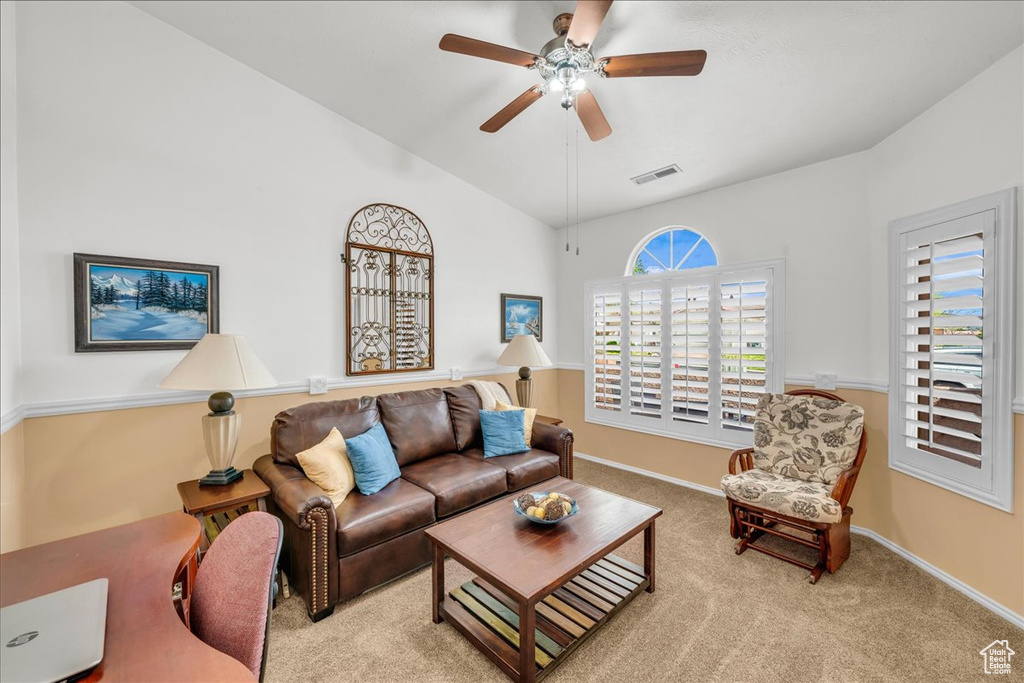 Carpeted living area featuring baseboards, visible vents, vaulted ceiling, and a ceiling fan