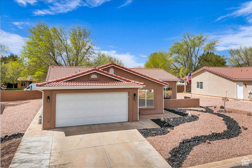 Mediterranean / spanish-style house featuring a tile roof, driveway, stucco siding, and an attached garage