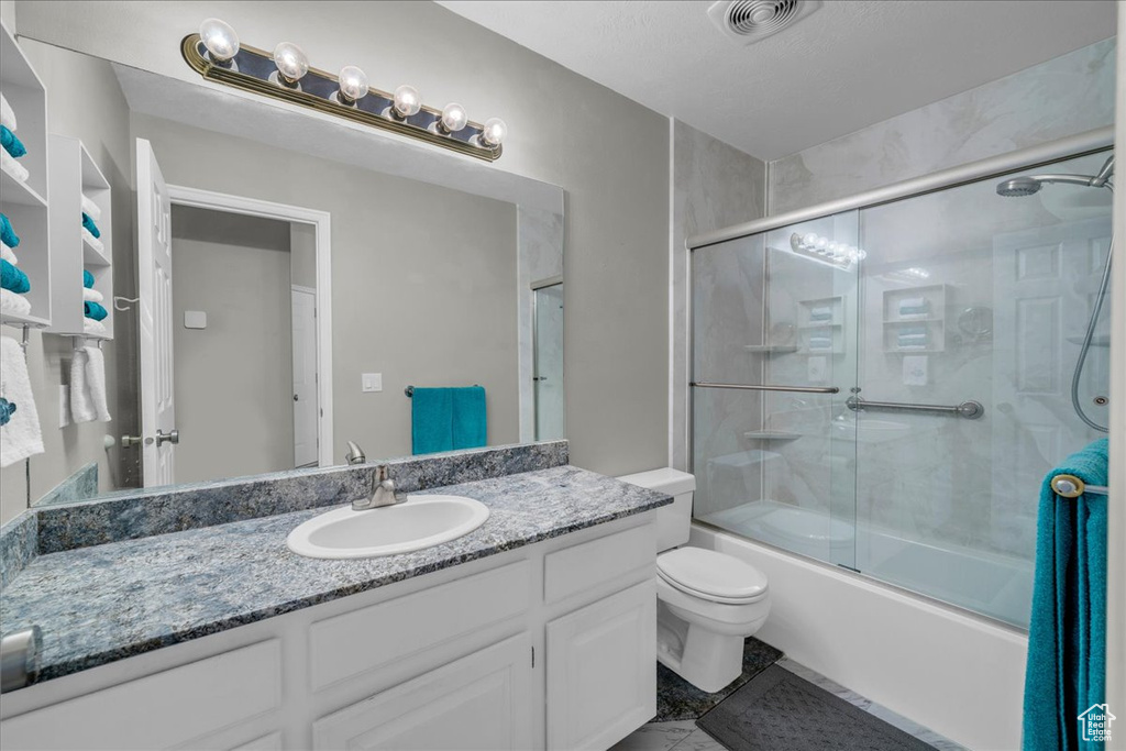 Full bath with toilet, vanity, enclosed tub / shower combo, and visible vents