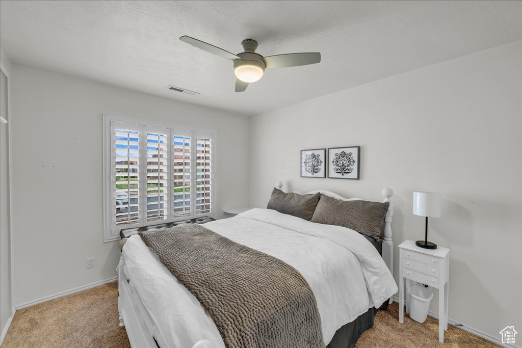 Carpeted bedroom featuring baseboards, ceiling fan, and visible vents
