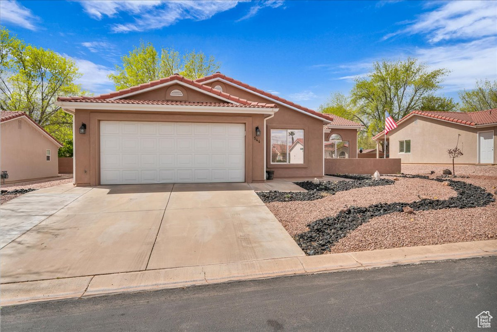 Mediterranean / spanish house with driveway, an attached garage, a tiled roof, and stucco siding