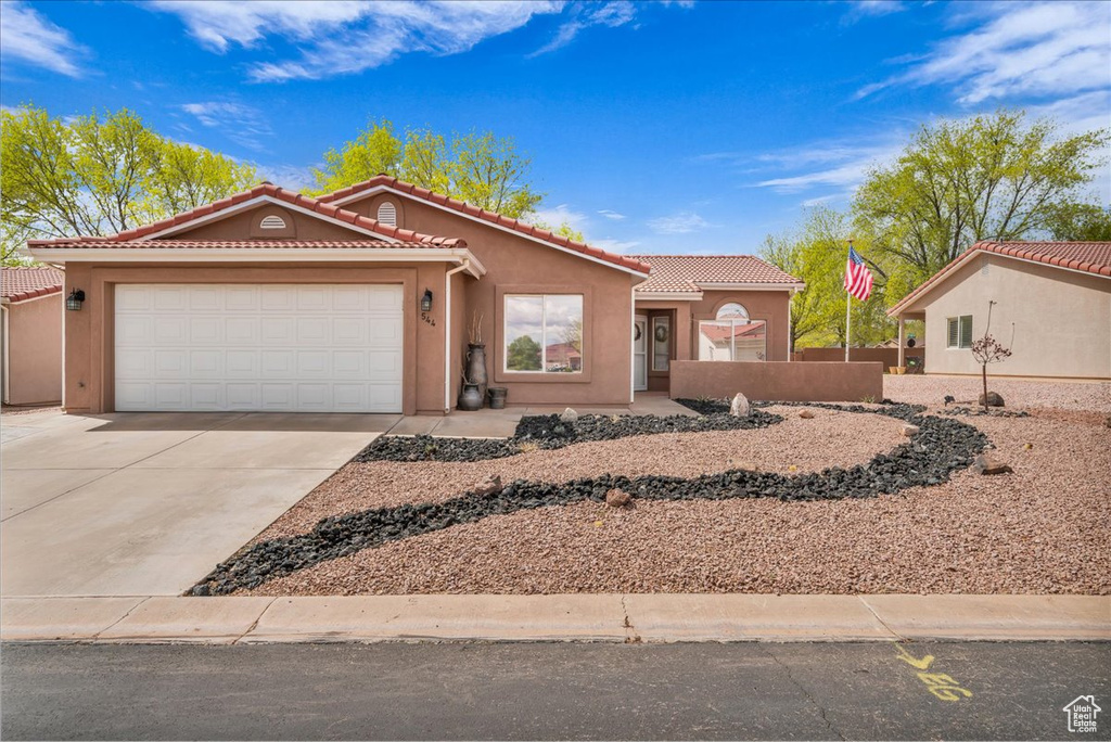 View of front facade featuring driveway, a tiled roof, and stucco siding