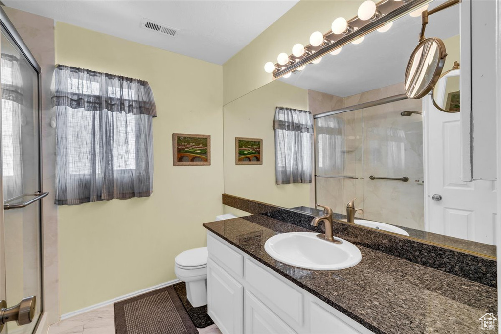 Bathroom featuring toilet, vanity, a shower stall, baseboards, and visible vents