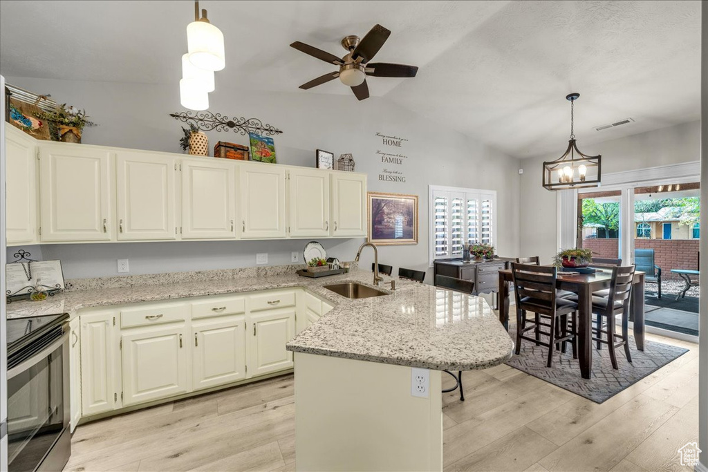 Kitchen with light wood finished floors, electric stove, a sink, and a peninsula