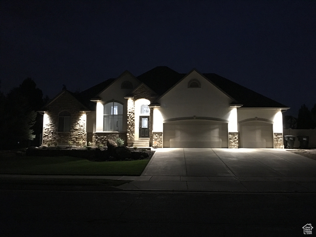 French country inspired facade featuring stone siding, concrete driveway, a garage, and stucco siding
