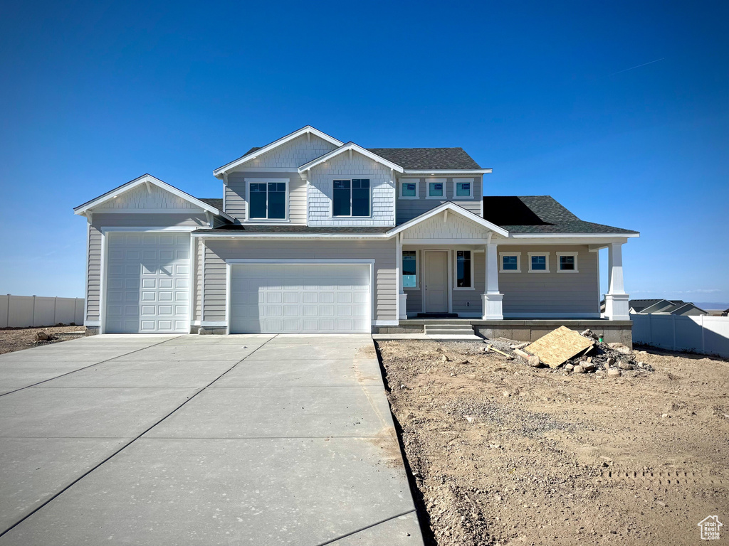 View of front facade with a garage, fence, covered porch, a shingled roof, and driveway