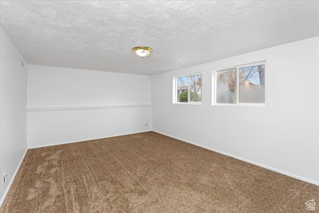 Carpeted spare room featuring baseboards and a textured ceiling