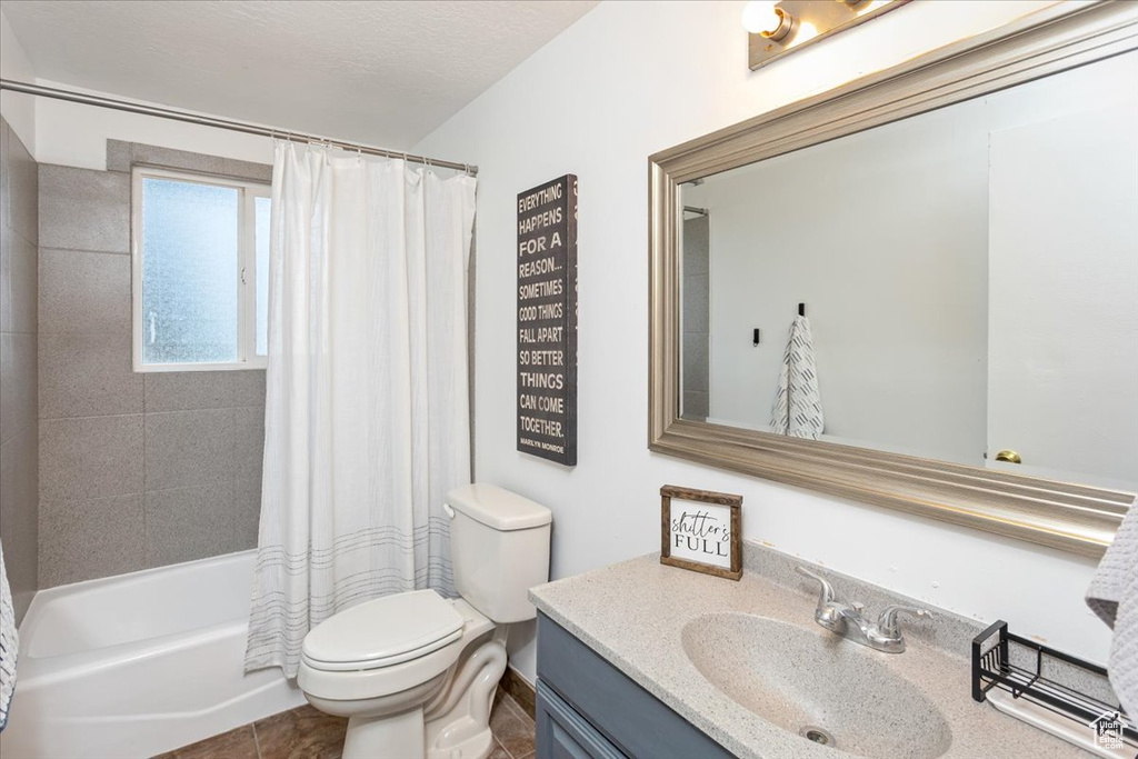 Bathroom with shower / bath combo, a textured ceiling, toilet, vanity, and tile patterned flooring