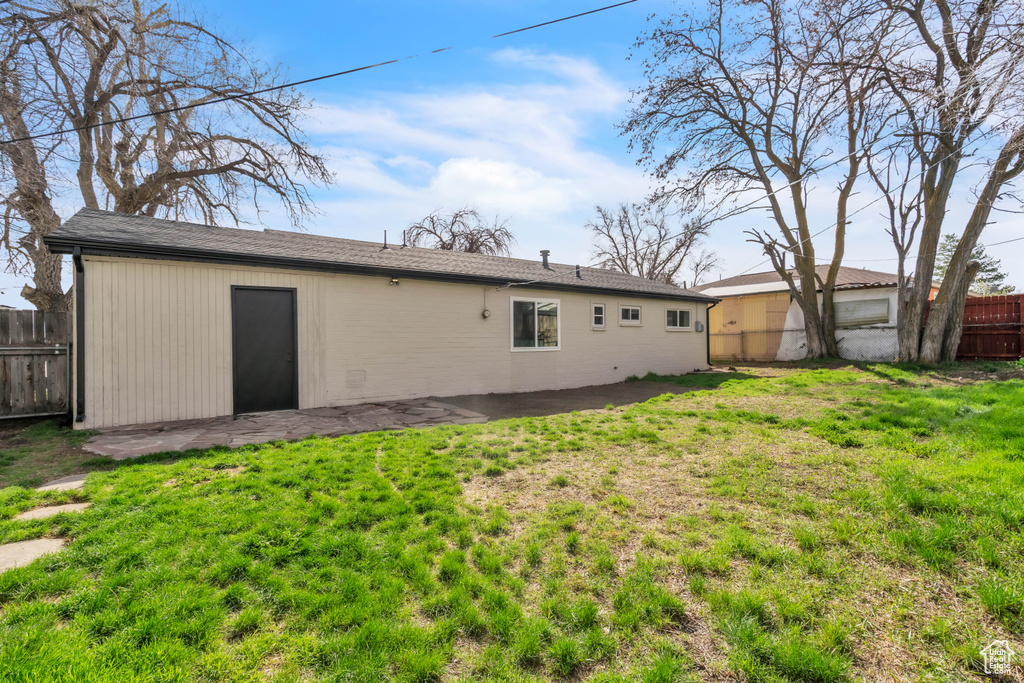 Rear view of house with a patio area, a lawn, and fence