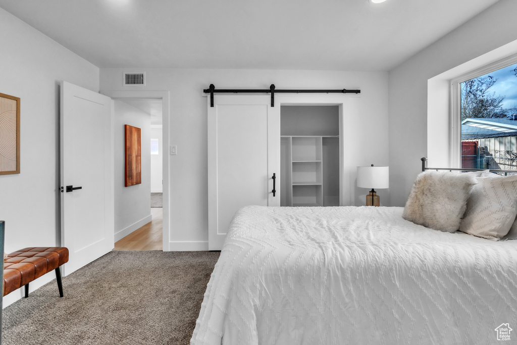 Carpeted bedroom with baseboards, visible vents, and a barn door