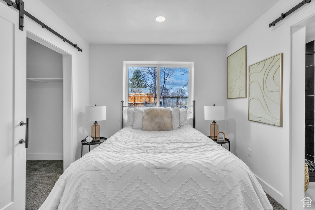 Bedroom featuring baseboards, a barn door, a closet, and carpet floors