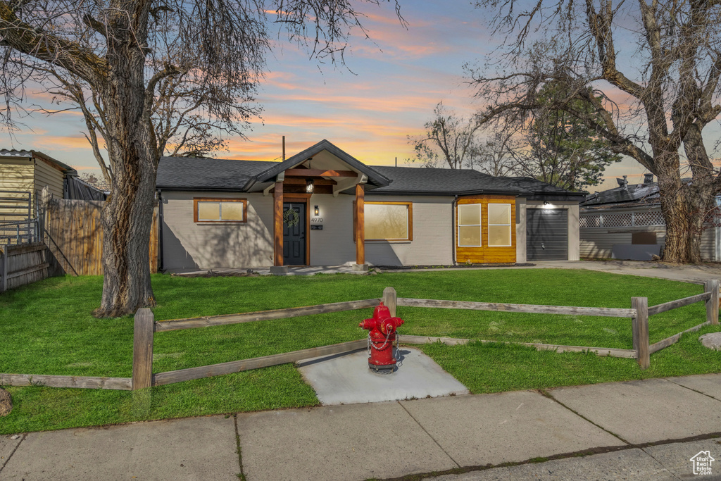 Mid-century inspired home with driveway, a garage, fence, and a lawn