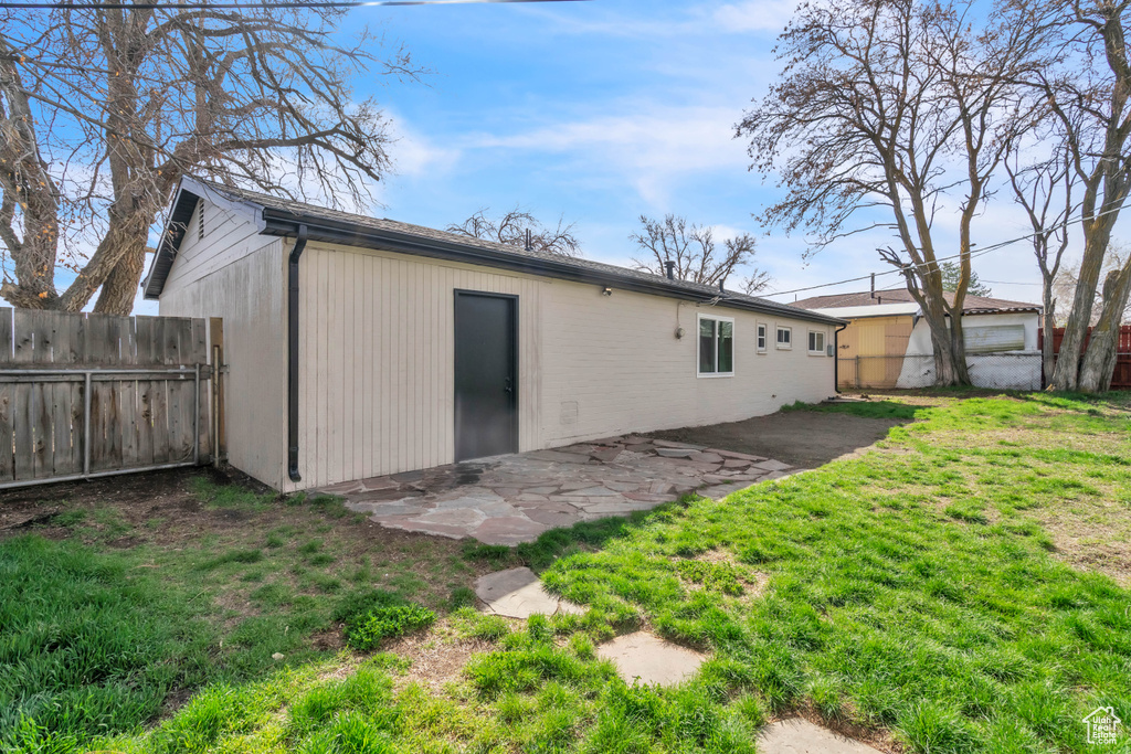 Rear view of property featuring fence, a patio, and a yard