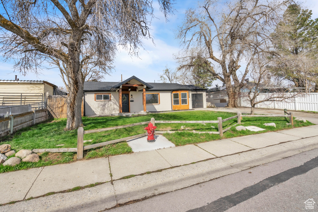 Mid-century inspired home featuring driveway, a front yard, fence, and a garage