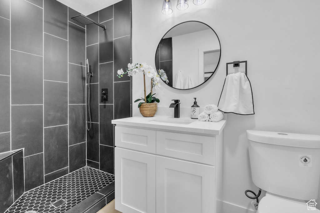 Full bathroom with a tile shower, toilet, and vanity