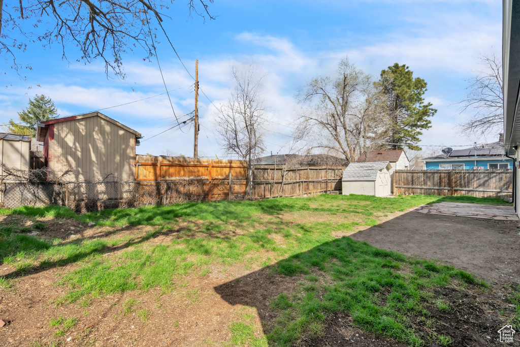 View of yard with a storage unit, a patio area, a fenced backyard, and an outdoor structure