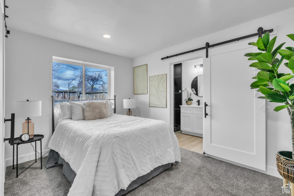 Bedroom with recessed lighting, baseboards, connected bathroom, a barn door, and light wood-style flooring
