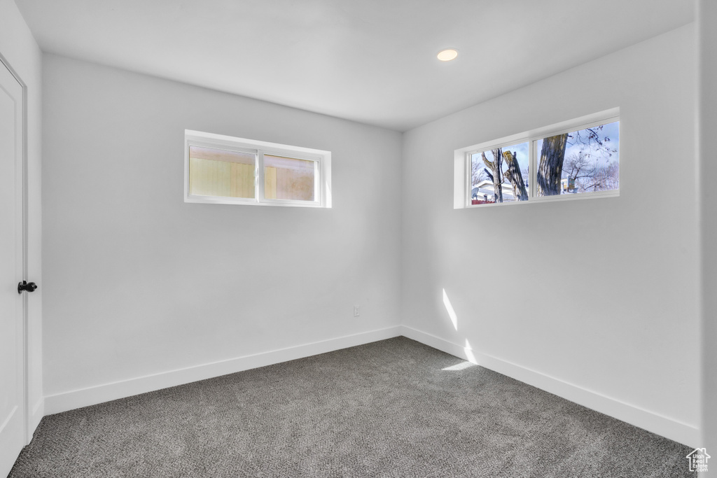 Empty room with plenty of natural light, baseboards, and dark carpet