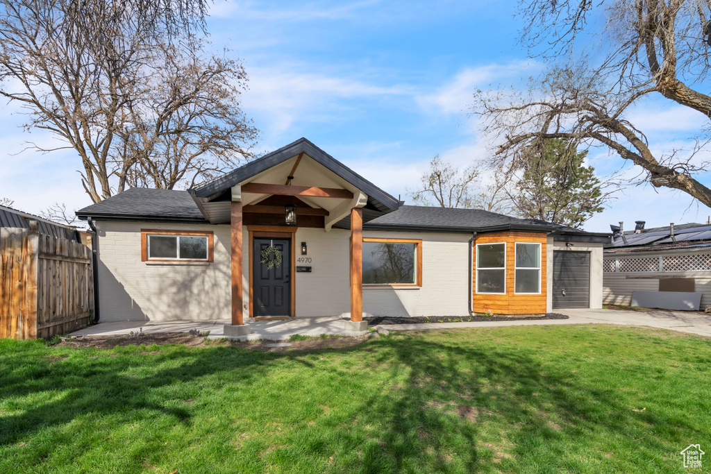 View of front of house with driveway, a garage, fence, and a front yard