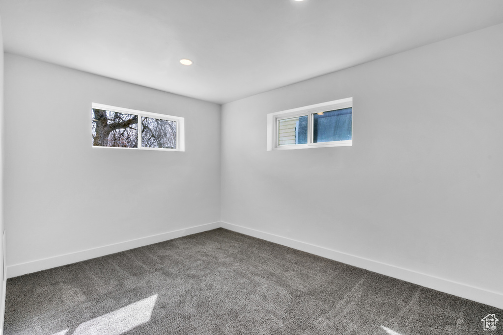 Empty room with baseboards, dark carpet, and recessed lighting