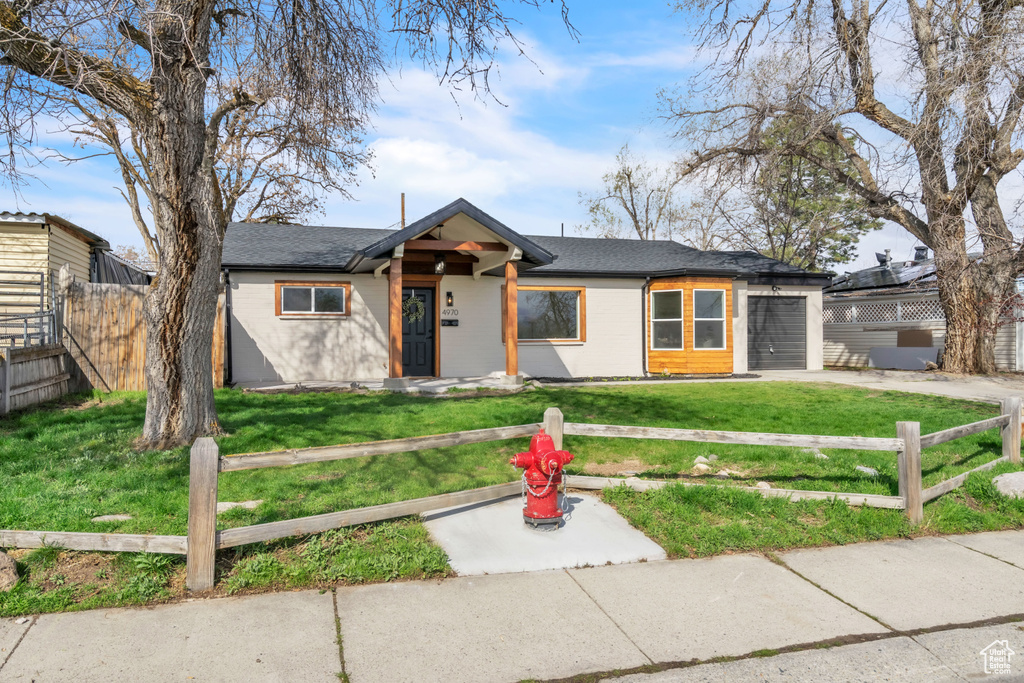 Mid-century home with an attached garage, fence, and a front lawn