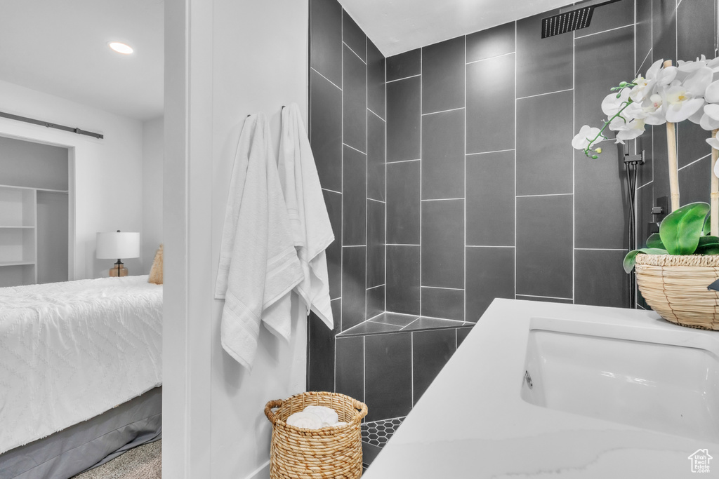 Bathroom with a sink, a tile shower, and recessed lighting