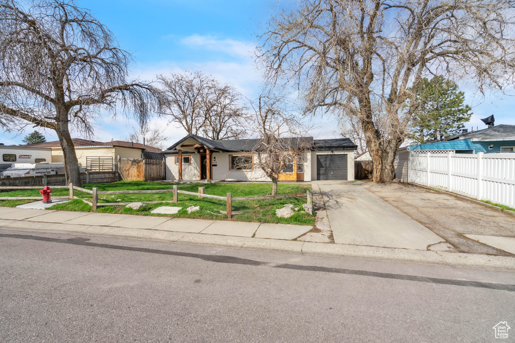 Mid-century modern home with driveway, a garage, a fenced front yard, and a front yard