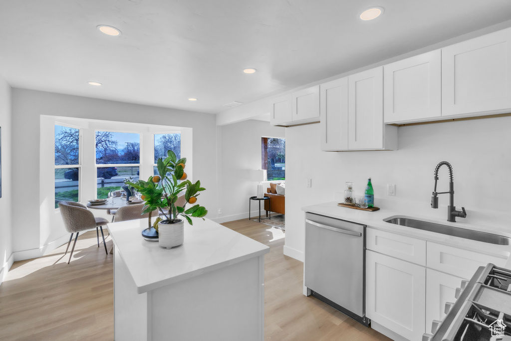 Kitchen featuring light countertops, stainless steel dishwasher, a sink, light wood-type flooring, and stove